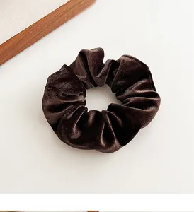 Detailopname van donkerbruine fluwelen scrunchie met zachte textuur op een lichte basis