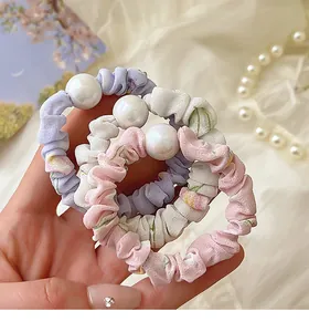 Détail de chouchous en mousseline fleurie avec perles en violet, crème et rose tendre