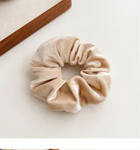 Detailopname van champagne fluwelen scrunchie met luxe textuur en elegante plooien