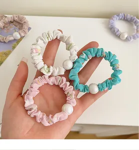 Vue détaillée des chouchous à fleurs avec grandes perles et texture de tissu plissé