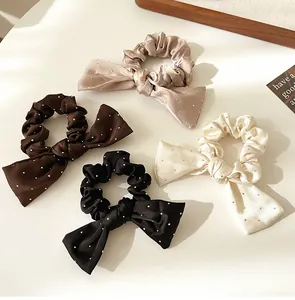 Gros plan de quatre chouchous avec nœuds en strass en marron, noir, beige et champagne
