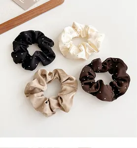 Dettaglio di quattro elastici in raso nero, bianco, oro e marrone con strass delicati