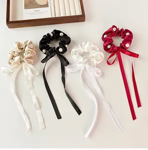 Detailed flat lay of satin scrunchies with faux pearls and long ribbons in four colors