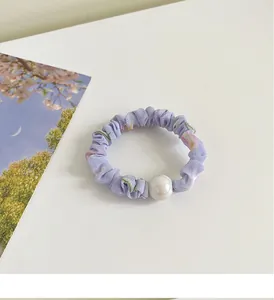 Détail d'un chouchou floral violet clair avec un élégant accent de perle