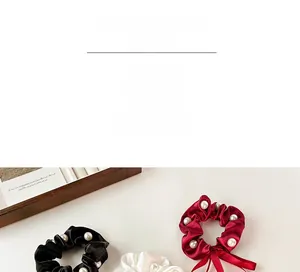 Detail of satin pearl scrunchies in black, white, and burgundy with ribbon bows