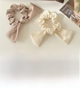 Détail d'un chouchou en satin avec strass et longs rubans en couleur champagne