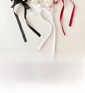 Close-up of silk ribbon hair ties with pearls in black, white and deep red colors