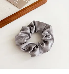 Dettaglio dell'elastico in raso grigio argento con strass su sfondo bianco