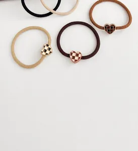 Detail of high-elastic scrunchies with checkered heart pendants in neutral earth tones