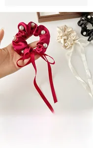 Close-up of elegant satin bow hair ties with pearl accents in burgundy and black