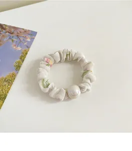 Détail d'un chouchou à fleurs blanches avec perle sur un fond de style épuré