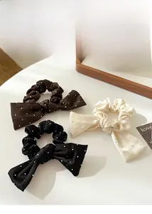Détail de chouchous en satin avec nœuds en strass en noir, marron et crème