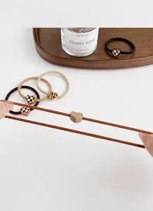 Detail of high-elasticity hair ties with heart charms in coffee and checkered patterns