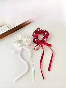 Detail of satin scrunchies with white pearls and long ribbons in white and burgundy