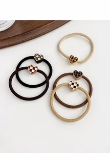 Macro view of five heart-shaped checkered elastic hair ties in neutral earth tones