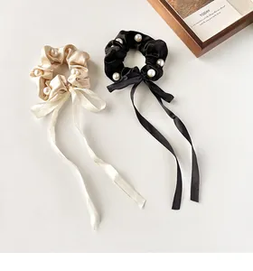 Detail of silk bow hair scrunchies with white pearls in cream and black colors