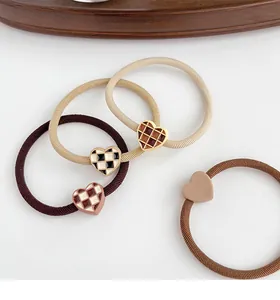 Detail of four high-elastic heart hair ties in neutral tones with checkered patterns