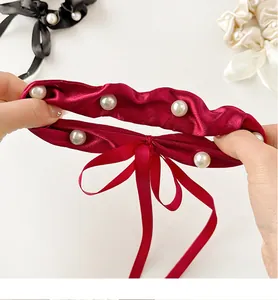 Detail showing the elastic stretch and satin texture of this bow hair tie with pearls