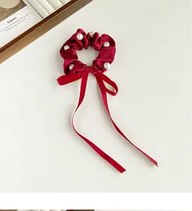 Close-up of wine red satin scrunchie with white pearl accents and long ribbon bow