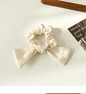Détail d'un chouchou en soie crème avec strass et un nœud élégant