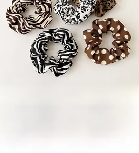 Flat lay of five patterned scrunchies including leopard, zebra, and polka dot prints