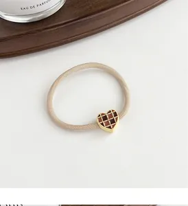 Detail of high-elastic scrunchie with heart-shaped checkered charm on a wooden tray