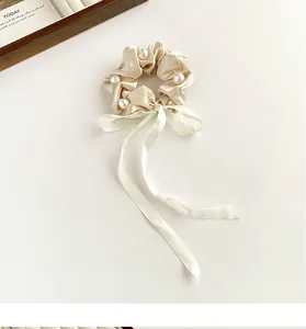 Detail of cream satin hair scrunchie with faux pearls and elegant long ribbon streamers