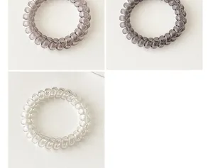 Detailed view of spiral telephone cord hair ties in gradient grey and transparent colors