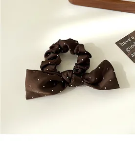 Détail du chouchou à nœud marron à pois avec texture satinée et perles brillantes