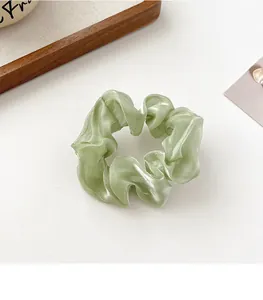 Nahaufnahme eines perlmuttfarbenen mintgrünen Haargummis aus glänzendem Organza-Stoff