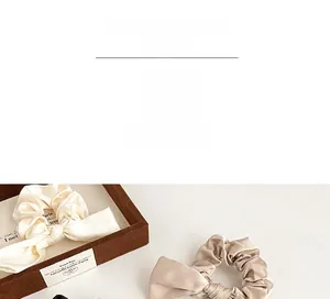 Détail de chouchous élégants en satin champagne et beige sur un plateau en bois