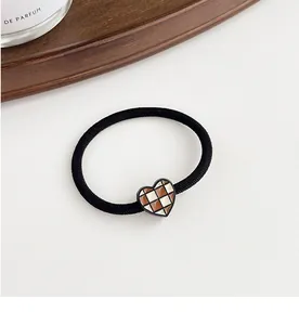 Close-up of a high-elastic hair tie featuring a brown checkered heart-shaped pendant