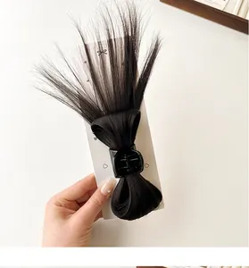 Close-up of black synthetic fiber hair claw clip with bow design and messy bun styling