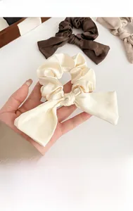 Détail de la texture satinée brillante et du design élégant du chouchou à nœud crème