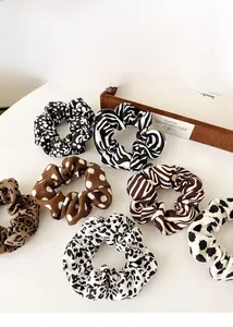 Close-up of leopard and animal print scrunchies set on a vintage wooden box