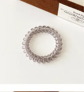 Detailed view of smoky grey spiral hair tie on a minimalist off-white surface