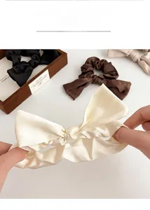 Vue détaillée de chouchous en satin à nœud en crème marron et noir à texture soyeuse