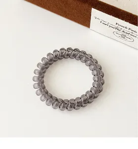 Macro shot of smoky grey spiral hair tie with glossy finish on a textured background