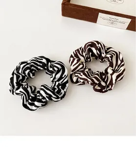 Close-up of zebra pattern scrunchies set in brown and black on a minimalist background