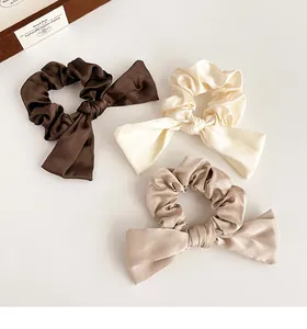 Lot de 3 chouchous en satin avec nœuds en marron, crème et beige sur fond blanc
