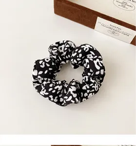 Detail of French vintage scrunchie with black and white floral pattern on ivory background