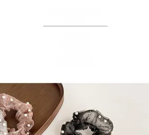 Détail de chouchous en organza rose et noir avec perles blanches sur plateau en bois