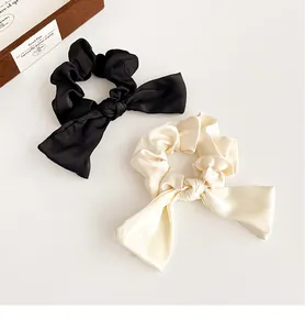 Détail de chouchous élégants en satin crème et noir avec une texture lisse et brillante