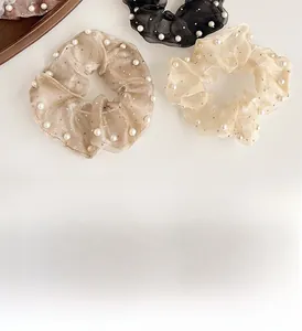 Vue à plat de chouchous en organza avec perles blanches en noir et champagne