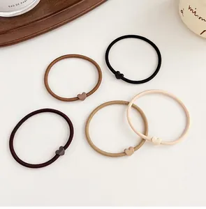 Close-up of five earth-toned elastic hair ties with matte heart-shaped charms