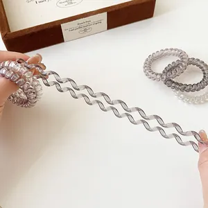 Stretchy grey gradient spiral hair ties shown being pulled to demonstrate elasticity