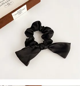 Gros plan du chouchou nœud en satin noir élégant avec texture soyeuse et décor bois