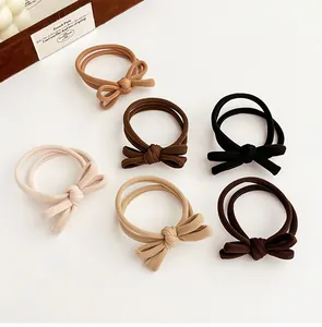Detail of six bow-knot hair ties in neutral tones showing elastic texture and stitching