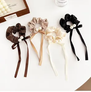 Detailed view of four satin bow scrunchies with pearls and ribbons in assorted colors