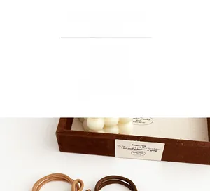 Detail of coffee brown elastic hair ties with seamless design on a velvet tray